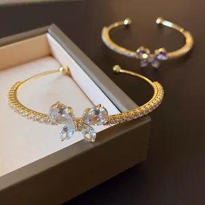 Détail d'un bracelet jonc ouvert papillon en or avec pierres de zircon