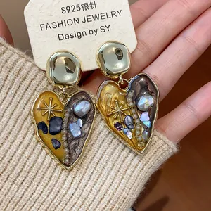 Dettaglio di orecchini vintage a forma di cuore con perle e finiture in oro metallizzato