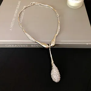 Zoom sur un collier argenté irrégulier avec pendentif goutte en strass brillant