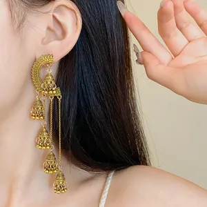 Close-up detail of vintage gold palace style long tassel earrings worn by model