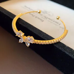 Vue macro détaillée d'un bracelet jonc ouvert papillon en zircon doré pour femmes