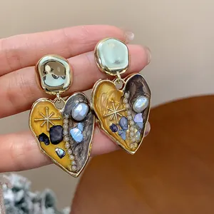 Dettaglio ravvicinato di orecchini a cuore vintage con pietre e perle naturali