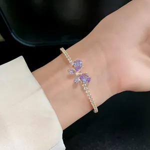 Détail d'un bracelet papillon en zircon doré avec des pierres violettes sur un poignet