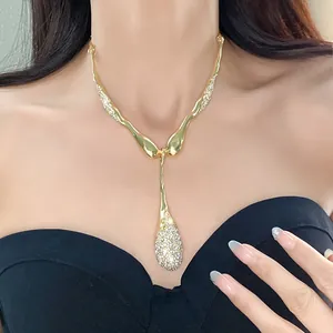 Élégant collier goutte doré avec strass scintillants porté sur le cou d'un mannequin.