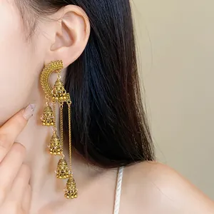 Detail view of long vintage gold-tone bohemian tassel chandelier earrings on a model