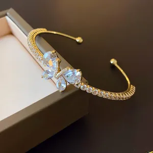 Détail d'un bracelet jonc ouvert luxueux avec papillon en zircon scintillant doré