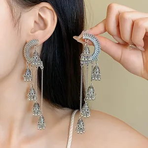 Close-up of vintage silver crescent earrings with Jhumka bell tassels on model.