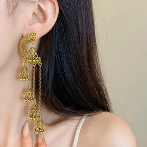 Close-up detail of vintage golden palace style jhumka bell tassel earrings worn by a model