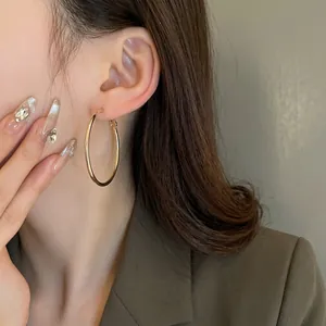 Minimalist large gold round hoop earrings worn on ear for elegant style