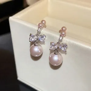 Elegant silver-toned bow knot pearl drop earrings featuring shimmering crystal accents