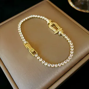 Close-up of an elegant gold-toned bracelet featuring a horseshoe buckle and sparkling zircons