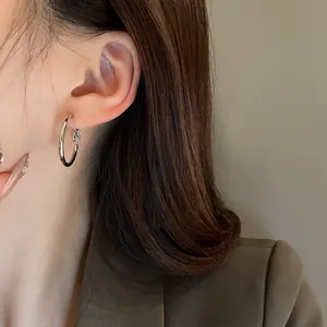 Detail view of minimalist silver hoop earrings worn by a model for a chic style.