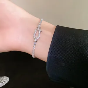 Detail view of a sparkling zirconia horseshoe buckle bracelet on a woman's wrist