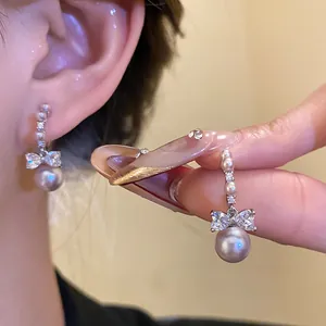 Close-up of elegant bow pearl drop earrings featuring crystals and pearls