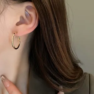 Minimalist gold-tone round hoop earrings worn by a model in a close-up detail view