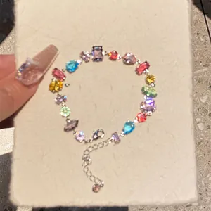 Detail of a dainty silver bracelet with colorful square and teardrop zircon stones.