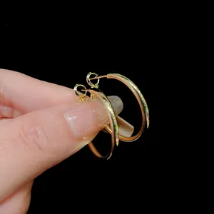 Detail view of minimalist gold hoop earrings featuring a polished metallic finish