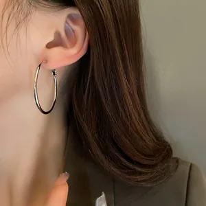 Elegant minimalist silver metal hoop earrings shown as worn on a model's ear detail