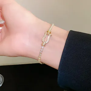 Detailed view of a gold tennis bracelet with a horseshoe buckle set with pavé cubic zirconia