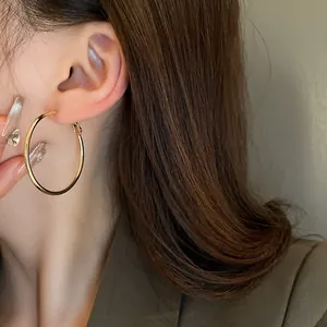 Detail macro view of a minimalist gold circular hoop earring worn by an Asian model.