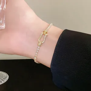 Close-up of a gold zircon horseshoe buckle bracelet worn on a wrist, elegant jewelry detail.