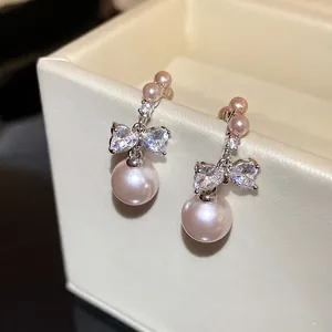 Close-up of elegant bowknot stud earrings with pink pearls and cubic zirconia
