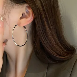 Close-up view of large minimalist silver geometric hoop earrings worn by a model
