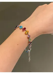 Detailed close-up showing a colorful zircon bracelet with square and water drop gems on a wrist.