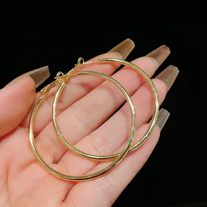 Detailed view of elegant minimalist gold-tone geometric large hoop earrings held in hand