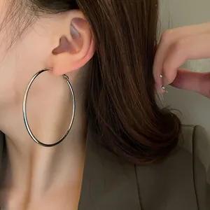 Detailed close-up view of minimalist large silver round metal hoop earrings on an Asian model