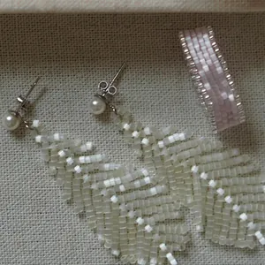 Detailed view of handmade beaded leaf earrings and matching pink woven ring set