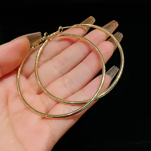 Detailed view of oversized gold-tone round hoop earrings showing size and metal finish
