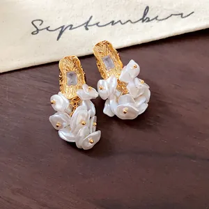 Detailed view of 18K gold-plated earrings with square gems and white petal clusters.