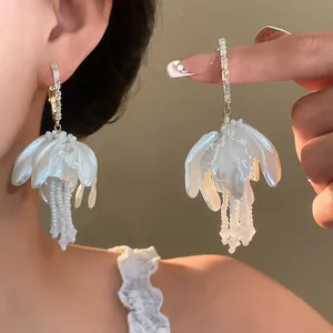 Detail of white jellyfish-shaped pearl earrings with 18K gold plated crystal hoops