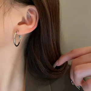 Detailed view of minimalist silver circular hoop earrings worn on a female ear model