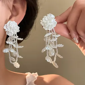 Close-up detail of elegant white flower tassel earrings with cascading resin petals