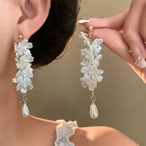 Detailed view of elegant white flower long drop earrings featuring a pearl teardrop.