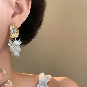 Elegant 18K gold-plated dangle earrings with white pearl clusters on an Asian model's ear