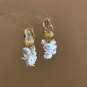Elegant 18K gold-plated dangle earrings featuring clear crystals and white petal shell charms.
