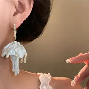 Detailed view of elegant white petal and pearl tassel earring with gold hoop
