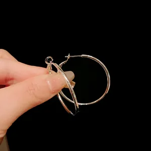 Macro detail of large silver metal hoop earrings for women on black background