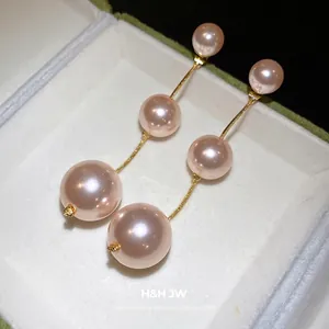 Elegant pink pearl drop earrings with gold-tone chain presented in a luxury white jewelry box.