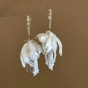 Close-up of elegant 18K gold plated flower earrings with white pearl petals and tassels