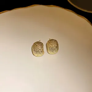 Irregular textured bean stud earrings in gold finish with silver needle backing