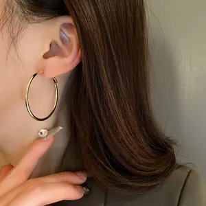 Detailed view showing a minimalist golden round hoop earring worn by an Asian female model