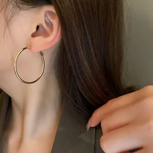 Close-up of a model wearing minimalist large gold-colored metal hoop earrings