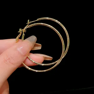Close-up of minimalist large gold hoop earrings with polished finish and needle clasp