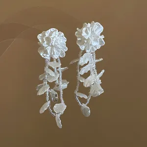 Detailed view of elegant white floral dangle earrings with bead strands and petal accents
