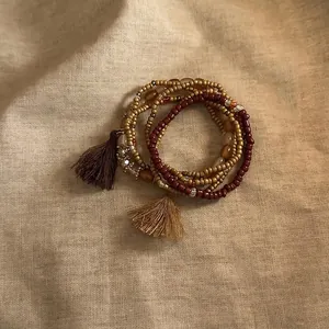 Detailed view of bohemian multi-layered beaded bracelets with tassels on linen fabric.