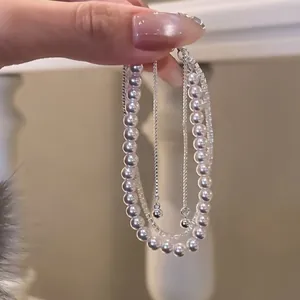 Dettaglio di un bracciale multistrato in stile francese con perle bianche e zirconi lucenti
